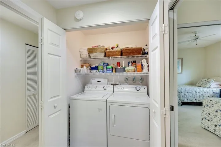 Laundry room with laundry area, baseboards, a ceiling fan, light colored carpet, and washer and dryer