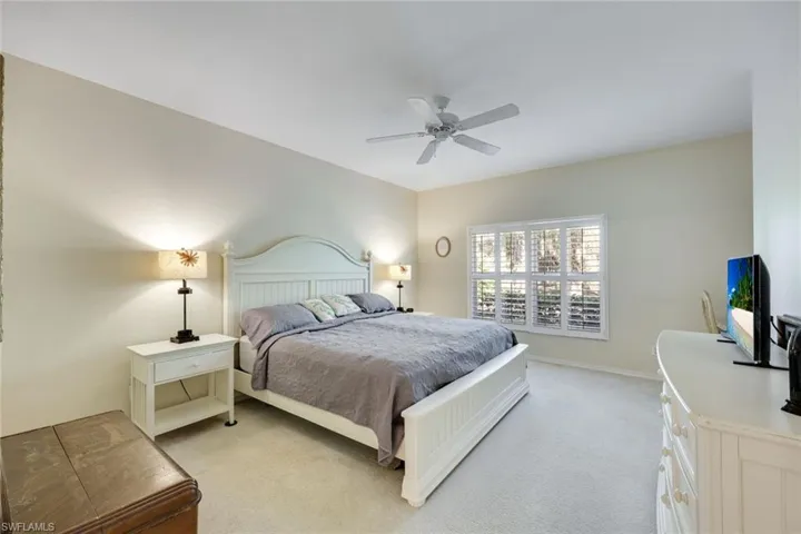 Bedroom with ceiling fan, baseboards, and light colored carpet