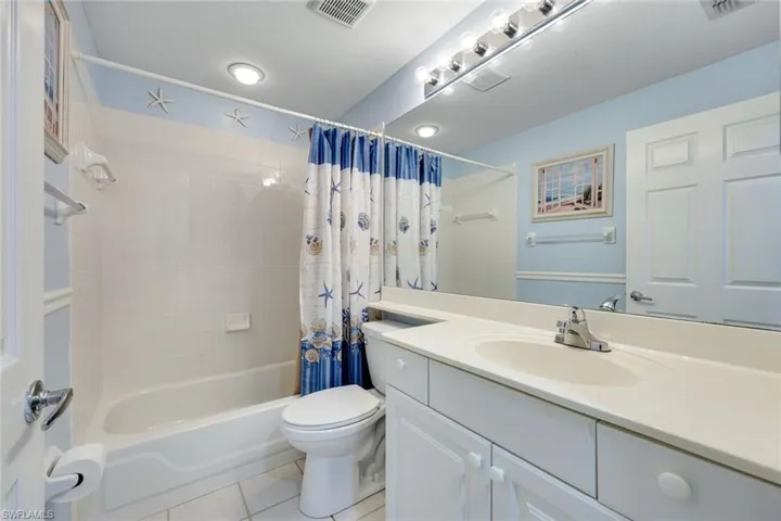 Full bathroom with toilet, vanity, tile patterned floors, and shower / bath combination with curtain
