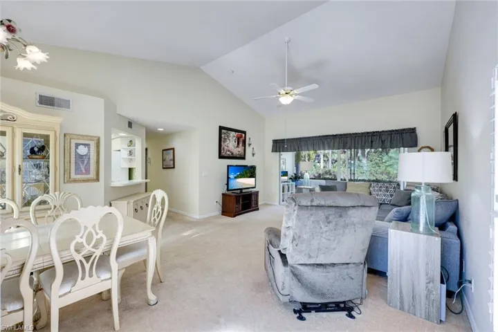 Living area, light carpet, ceiling fan, high vaulted ceiling.