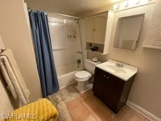 Full bathroom featuring toilet, tile patterned floors, vanity, and shower / bathtub combination with curtain