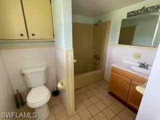 Full bathroom featuring vanity, tile patterned floors, toilet, and washtub / shower combination
