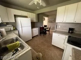 Kitchen featuring white cabinetry, sink, white appliances, and ceiling fan