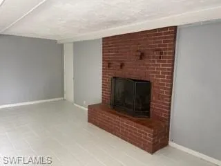 Unfurnished living room with a fireplace and a textured ceiling