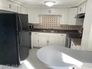 Kitchen featuring light tile patterned flooring, stainless steel appliances, sink, and white cabinets