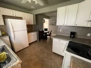 Kitchen with white cabinetry, sink, white appliances, and ceiling fan
