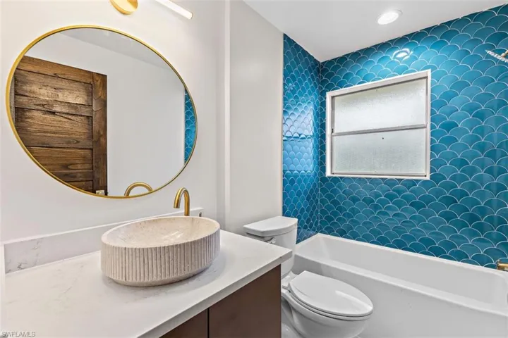Full bathroom featuring tiled shower / bath combo, toilet, and vanity