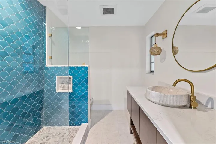 Bathroom with tiled shower, vanity, tile patterned flooring, and toilet