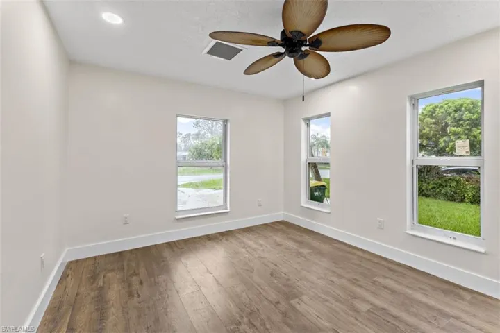 Spare room featuring ceiling fan, hardwood / wood-style flooring, and a healthy amount of sunlight