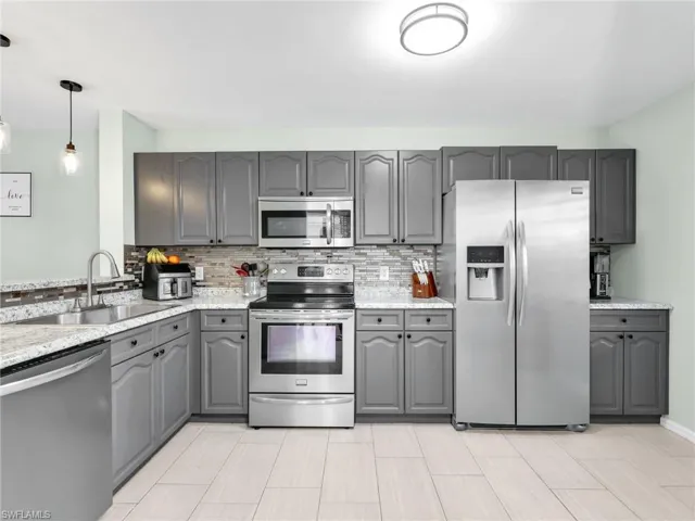 Kitchen featuring gray cabinetry, stainless steel appliances, and tasteful backsplash