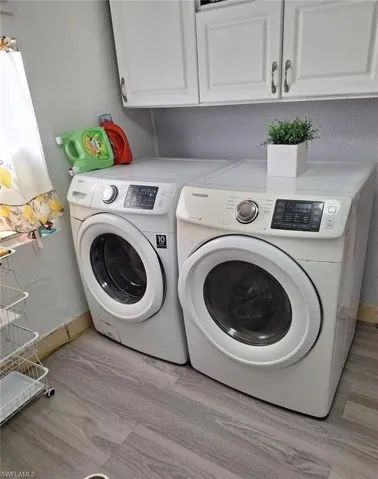 Laundry room with light hardwood / wood-style floors, cabinets, and separate washer and dryer