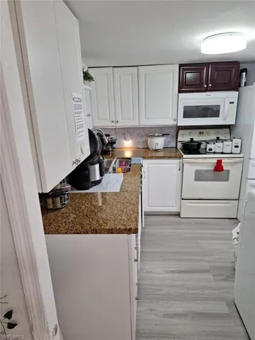 Kitchen with white cabinets, decorative backsplash, and white appliances