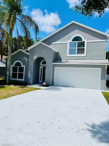 View of front of house with stucco siding, driveway, and a garage