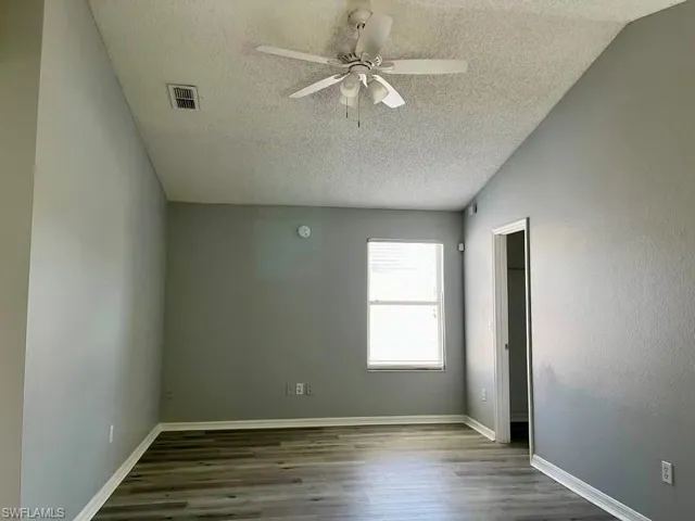 Empty room with baseboards, visible vents, ceiling fan, and wood finished floors