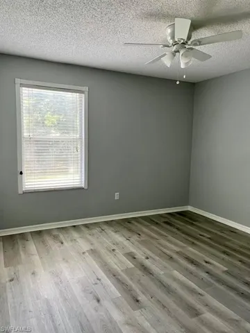 Spare room featuring baseboards, wood finished floors, ceiling fan, and a textured ceiling