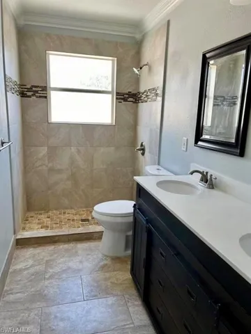 Full bath featuring ornamental molding, a sink, a tile shower, and toilet