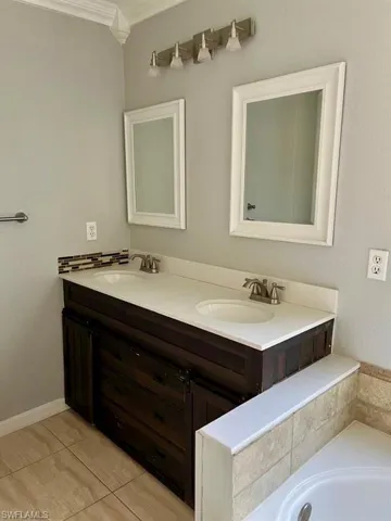 Full bath with double vanity, a bathing tub, a sink, and tile patterned floors