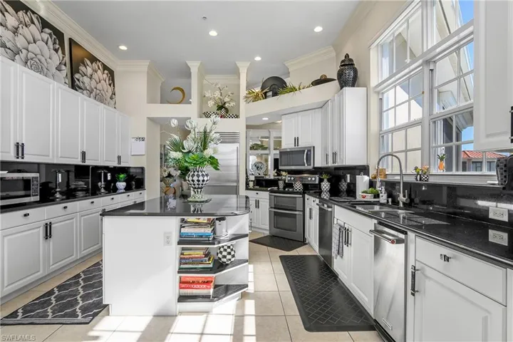 Kitchen featuring a sink, dark countertops, appliances with stainless steel finishes, and light tile patterned flooring