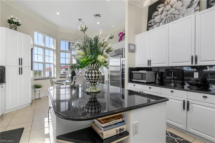 Kitchen with light tile patterned floors, visible vents, stainless steel appliances, white cabinetry, and crown molding