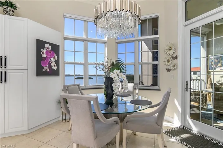 Dining area featuring light tile patterned flooring, a notable chandelier, and a water view