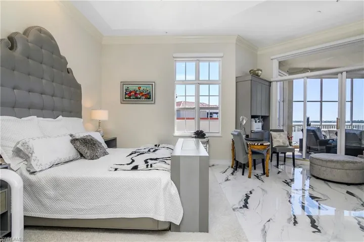 Bedroom featuring multiple windows, marble finish floor, and ornamental molding