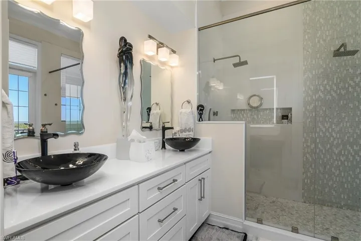 Bathroom featuring double vanity, a walk in shower, and a sink