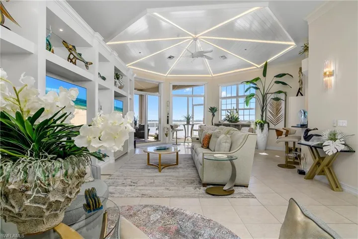 Living room featuring built in features, light tile patterned floors, baseboards, ornamental molding, and wood ceiling
