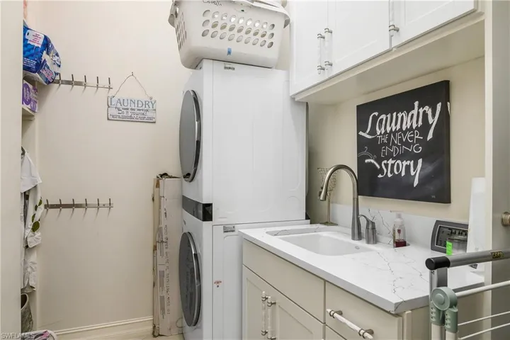 Laundry area with cabinet space, stacked washer / drying machine, and a sink