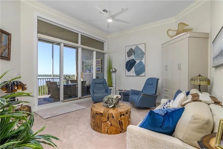Living area featuring carpet floors, ceiling fan, and crown molding