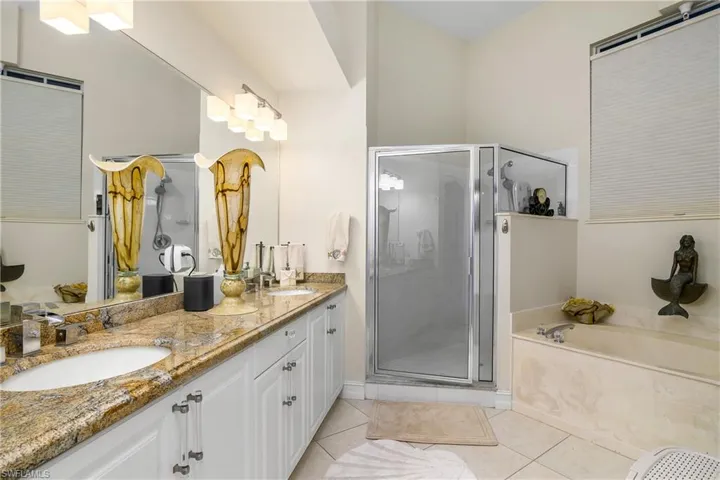 Full bathroom featuring tile patterned flooring, a shower stall, double vanity, and a sink