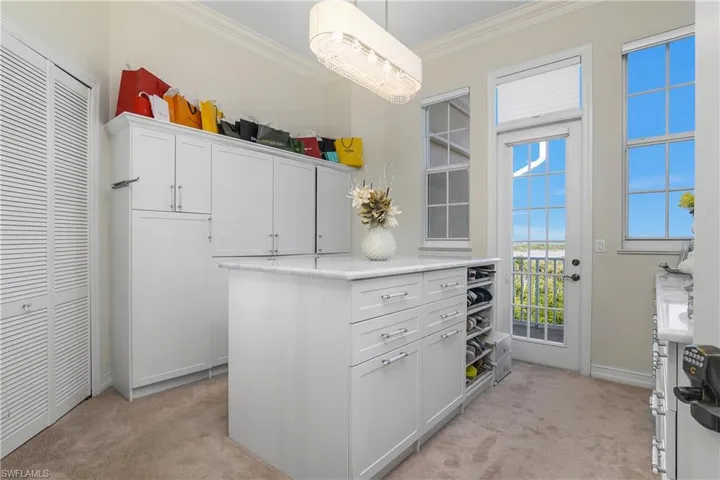 Kitchen featuring crown molding, white cabinets, light countertops, and light carpet