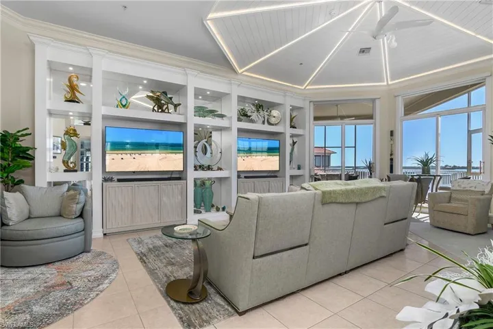 Living room featuring visible vents, built in shelves, light tile patterned flooring, and crown molding