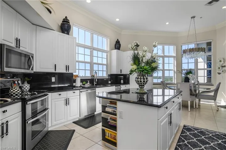 Kitchen featuring dark countertops, light tile patterned floors, tasteful backsplash, and appliances with stainless steel finishes