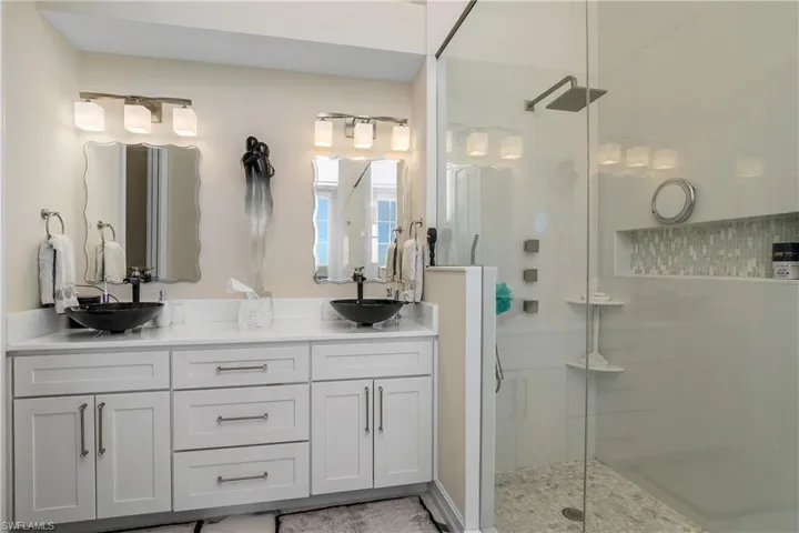 Full bath with a sink, a stall shower, and double vanity