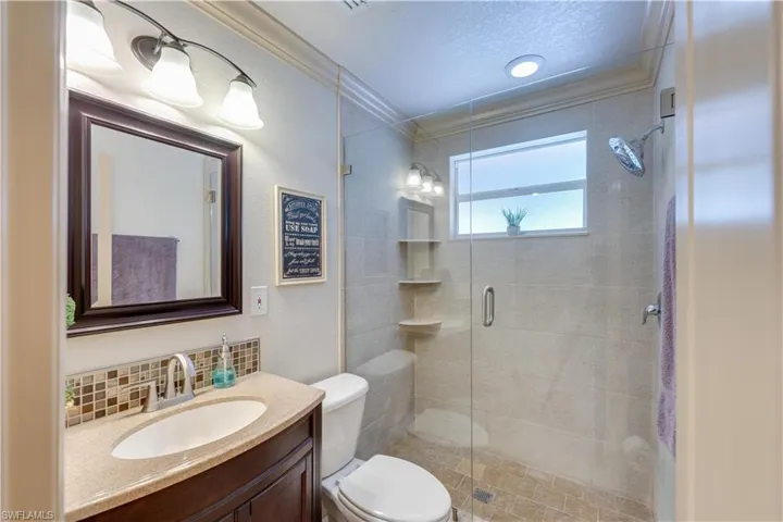 155 Evans Rd, LaBelle, FL 33935 Bathroom featuring vanity, a shower with door, crown molding, decorative backsplash, and toilet
