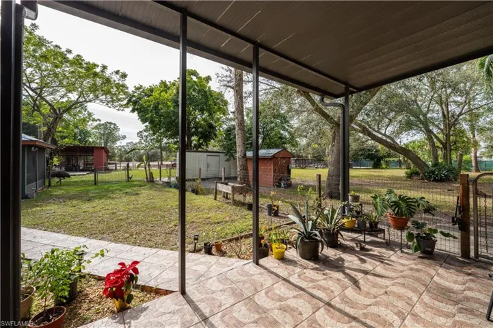 155 Evans Rd, LaBelle, FL 33935 View of patio leading to outdoor dining and recreation room, barn and storage sheds