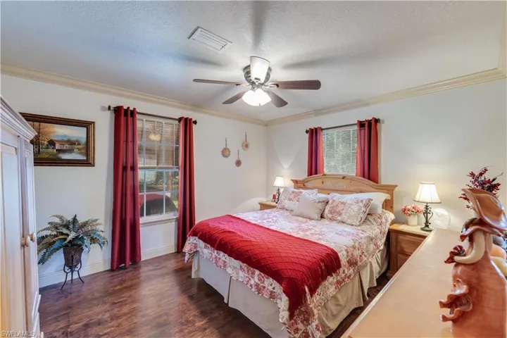 155 Evans Rd, LaBelle, FL 33935 Bedroom featuring ornamental molding, a textured ceiling, ceiling fan, and dark wood-type flooring
