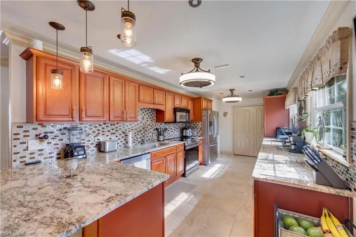 155 Evans Rd, LaBelle, FL 33935 Kitchen with pendant lighting, ornamental molding, appliances with stainless steel finishes, light stone counters, and kitchen peninsula