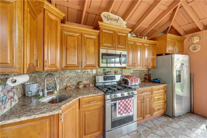 155 Evans Rd, LaBelle, FL 33935 Outdoor kitchen/party room with stone counters, lofted ceiling with beams, sink, decorative backsplash, and stainless steel appliances