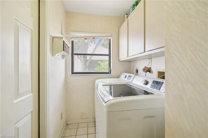 Laundry area with washing machine and dryer, cabinet space, and light tile patterned floors