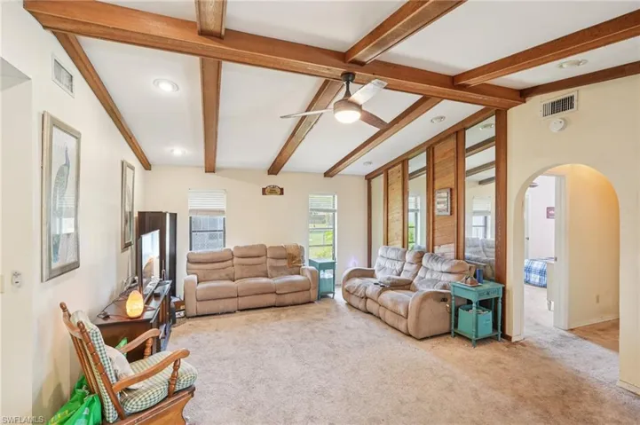 Living room with beamed ceiling, carpet flooring, arched walkways, a ceiling fan, and recessed lighting