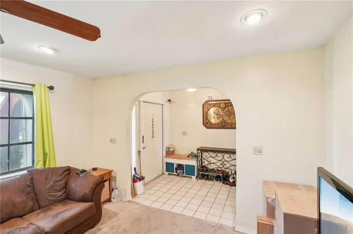 Living room featuring arched walkways, light carpet, and light tile patterned flooring
