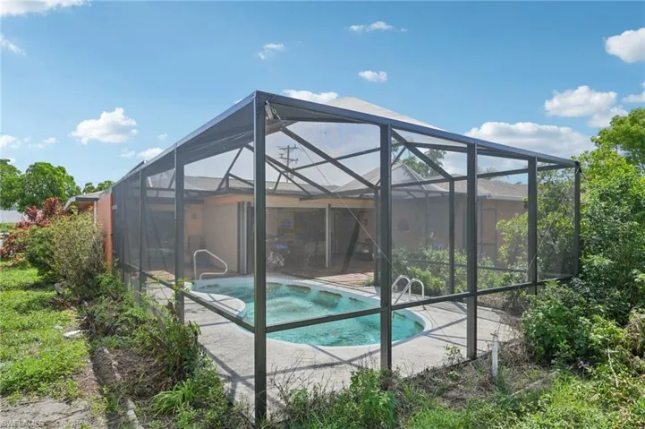Swimming pool featuring a hot tub, a patio, and a lanai