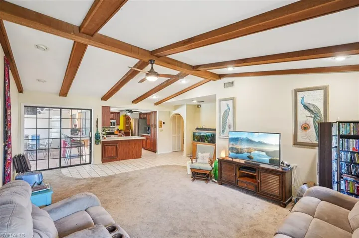 Living room with a ceiling fan, light carpet, arched walkways, and recessed lighting