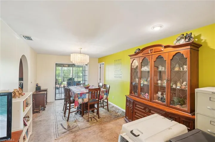 Dining area with arched walkways, light carpet, and a chandelier