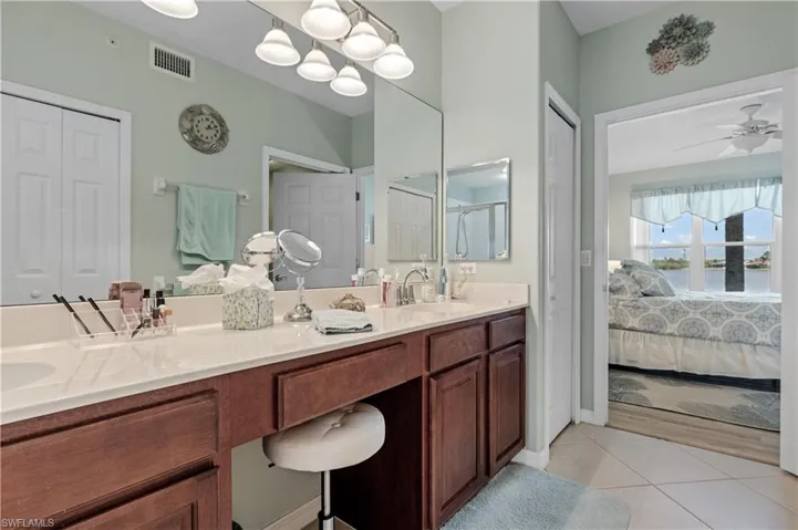 Ensuite bathroom with a closet, double vanity, and light tile patterned flooring