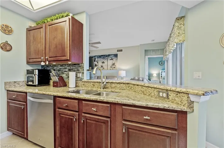 Kitchen featuring light stone countertops, dishwasher, a ceiling fan, tasteful backsplash, and a peninsula