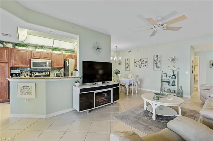 Living room featuring a ceiling fan, light tile patterned flooring, and hanging lights