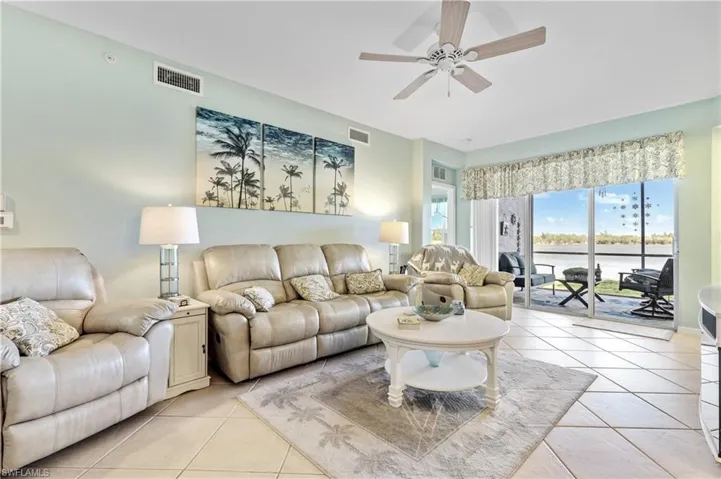 Living area with a ceiling fan, a water view, and light tile patterned floors