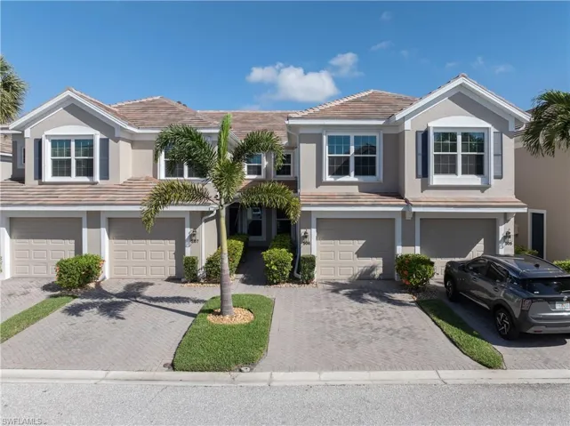 Traditional-style house with stucco siding, a tile roof, and a garage